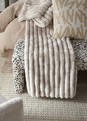 Fluffy beige throw blanket draped over a patterned chair