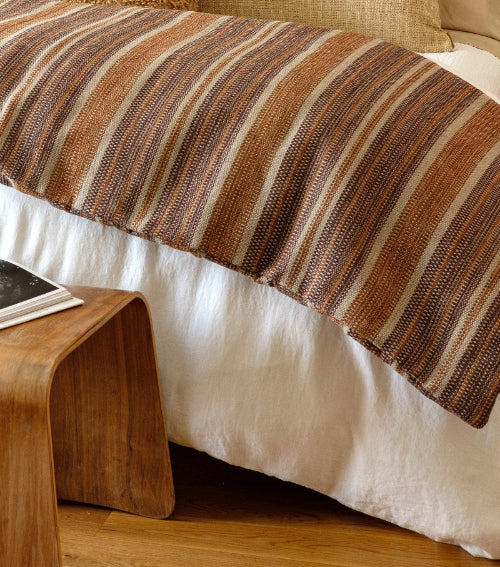 Striped blanket on a bed with a wooden nightstand and book
